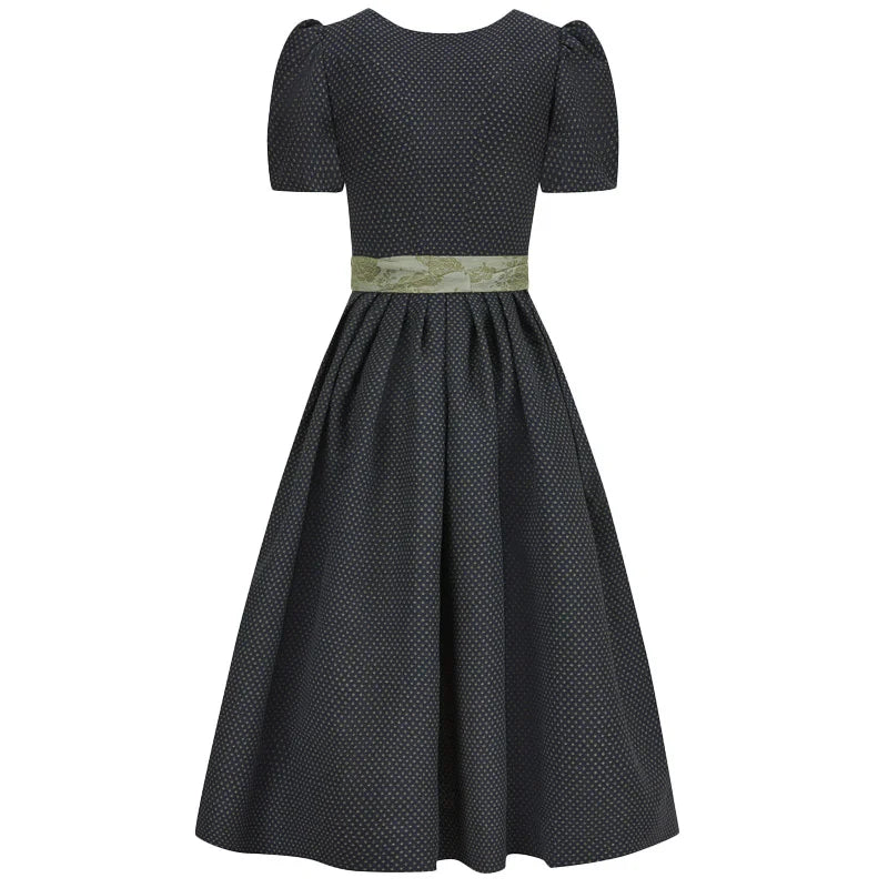 Black polka dot dirndl dress with a green belt on a white background