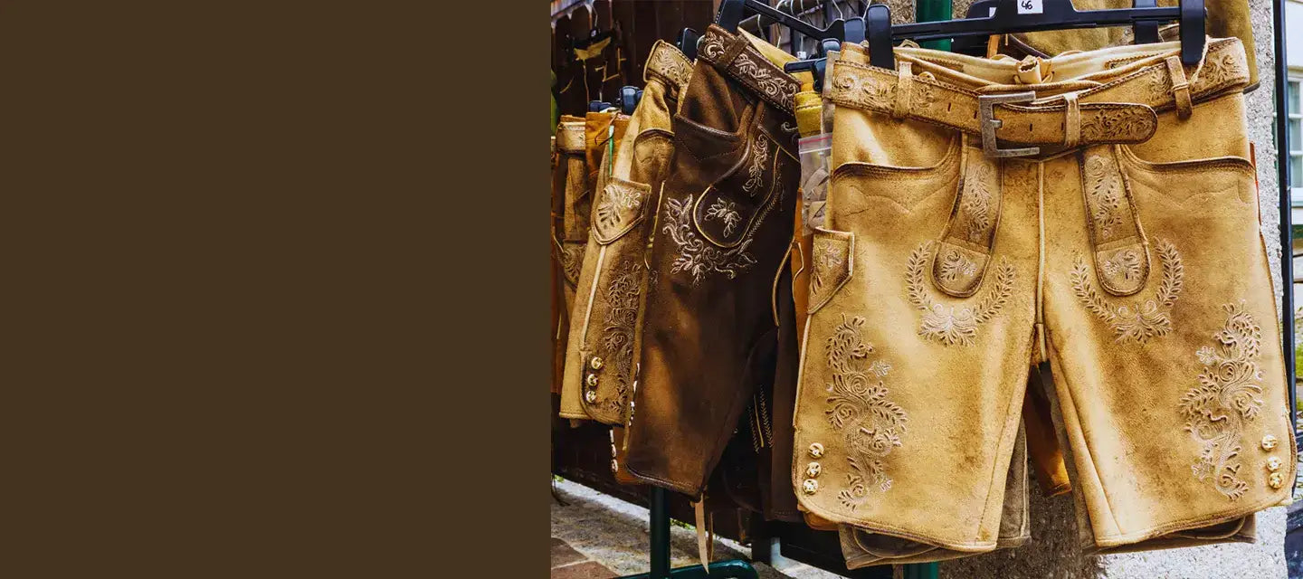 Gold Lederhosen shorts with decorative elements on a rack against a brown background