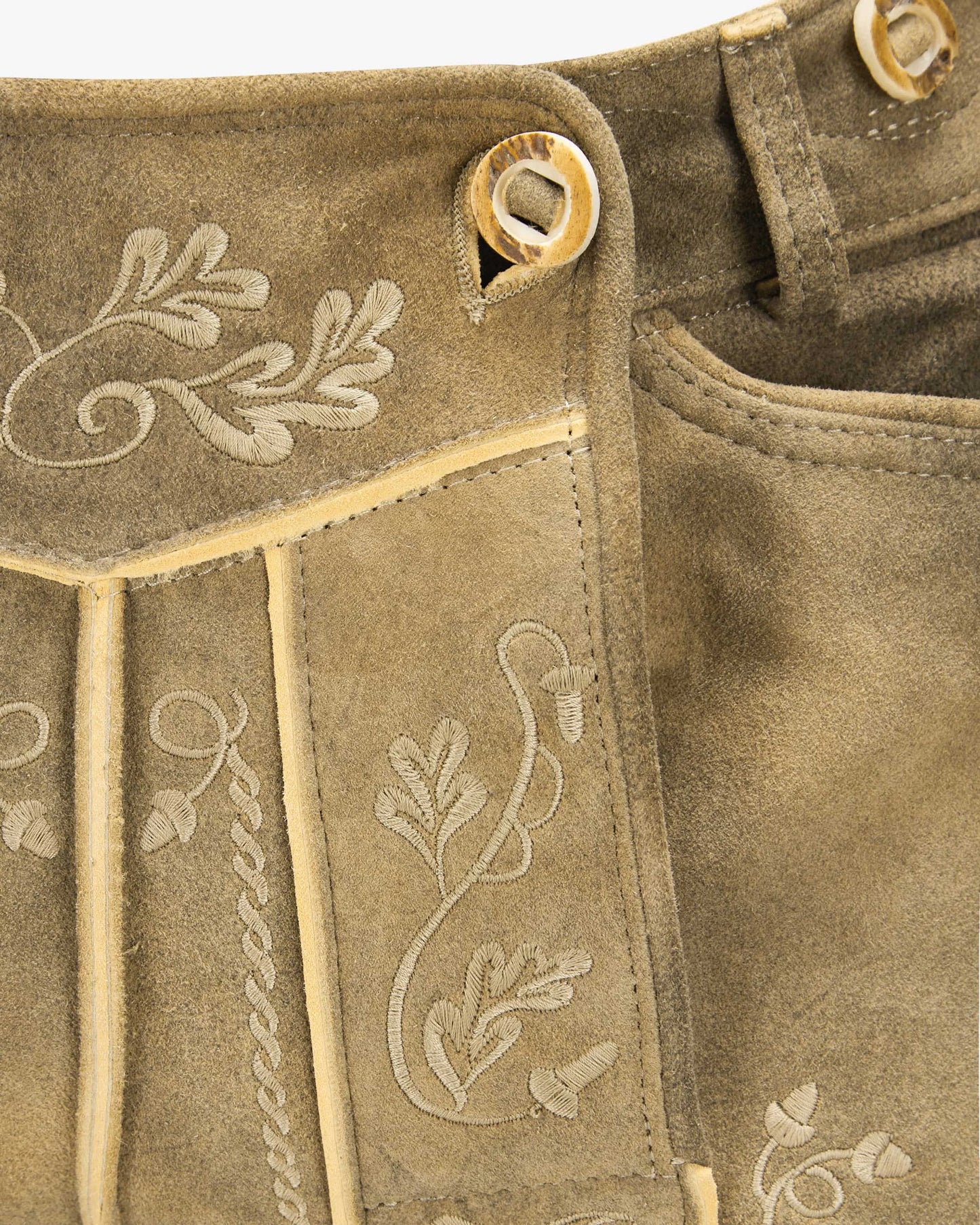 Close-up of brown fabric with embroidered floral patterns and button details.