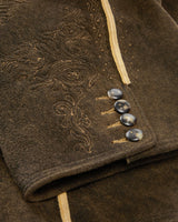 Close-up of a brown textured fabric with embroidered patterns and buttons.
