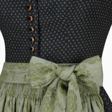 Close-up of a dark blue patterned top with a green floral skirt and ribbon.