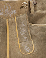 Close-up of brown leather pants with embroidery and button details