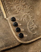 Close-up of a brown fabric with embroidered design and black buttons.