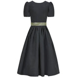 Black polka dot dirndl dress with a green belt on a white background 
