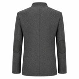 A dark gray textured wool-blend blazer shown from the back, featuring circular patchwork elbow patches on the sleeves and a clean collar.