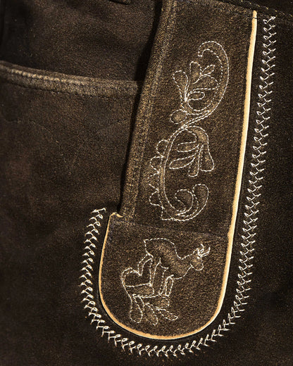 Close-up of a black leather jacket with intricate white embroidery on a dark background