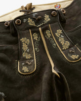 Close-up of dark brown leather pants with gold embroidery on a white background