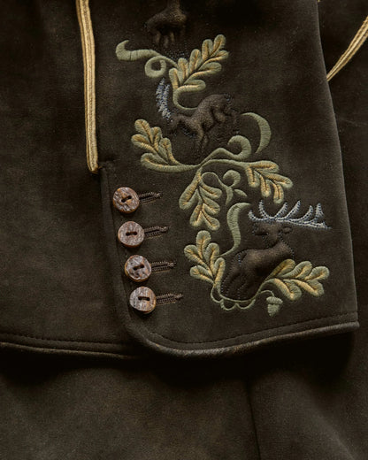 Embroidered design on a dark fabric with deer and foliage patterns.