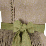 Close-up of a traditional outfit with a green ribbon and beige patterned fabric.