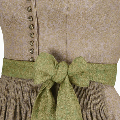 Close-up of a traditional outfit with a green ribbon and beige patterned fabric.