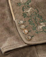 Close-up of a brown fabric with embroidered deer and foliage design.
