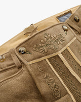 Close-up of a beige fabric with intricate embroidery and buttons on a white background