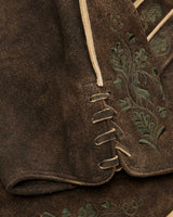 Close-up of a brown fabric with embroidered green leaves on a garment.