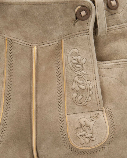 Close-up of brown leather pants with intricate stitching and a embroidered design.