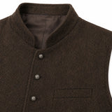 Close-up of a dark brown herringbone tweed vest with a mandarin collar, three dark buttons, and a welt pocket on the chest.