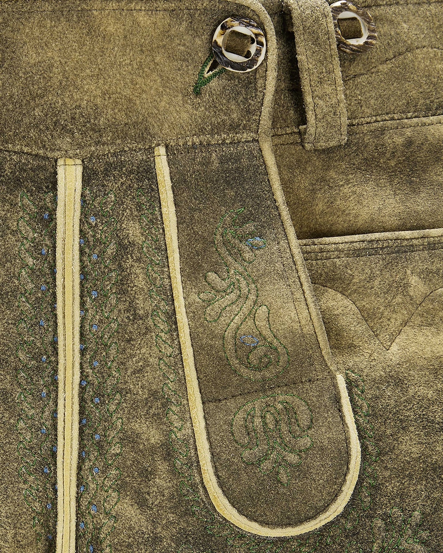 Close-up of a brown leather belt with decorative stitching on a textured fabric background