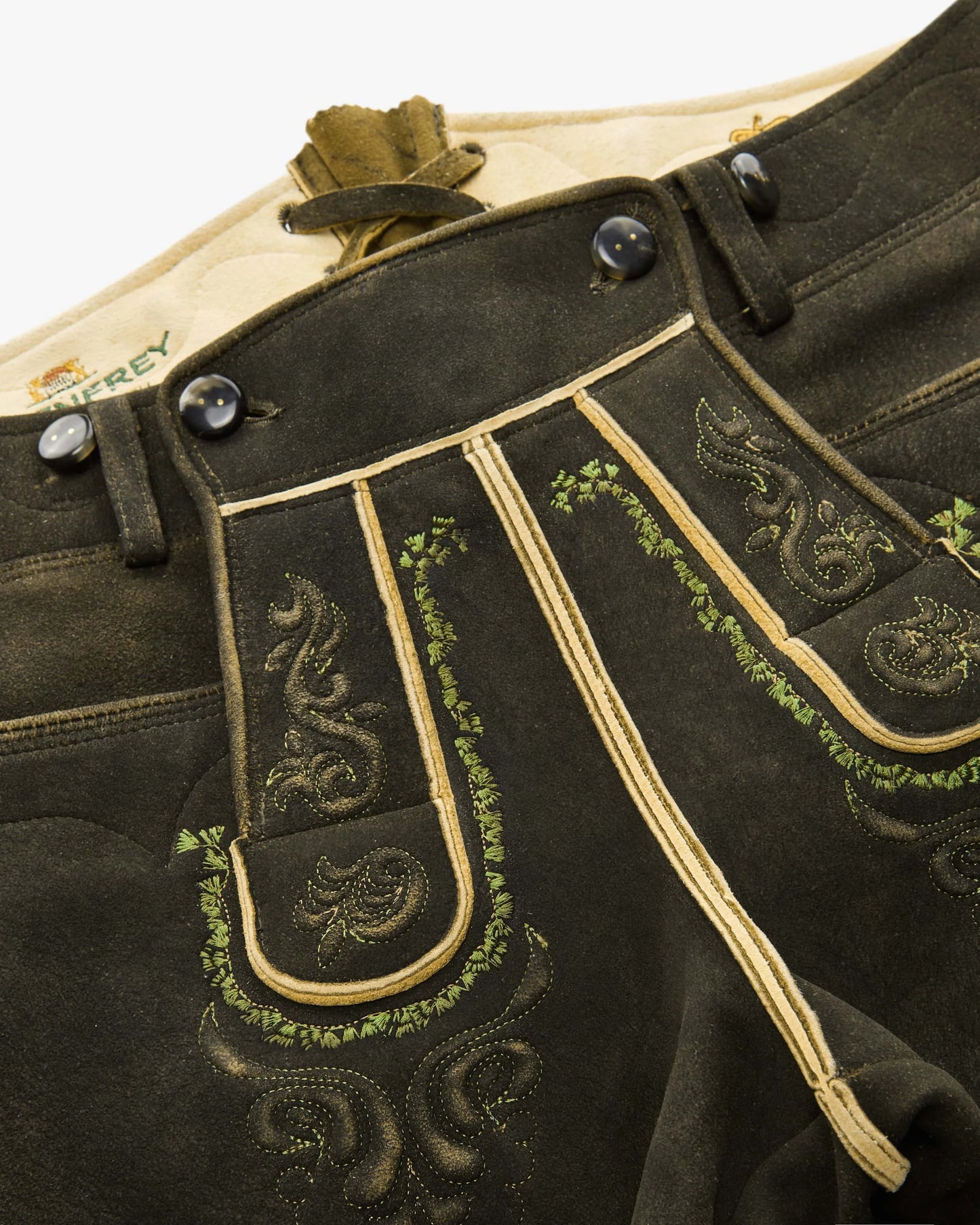 Traditional black leather shorts with gold embroidery on a white background