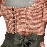 Red and white checkered dress with black buttons and green bow on a white background