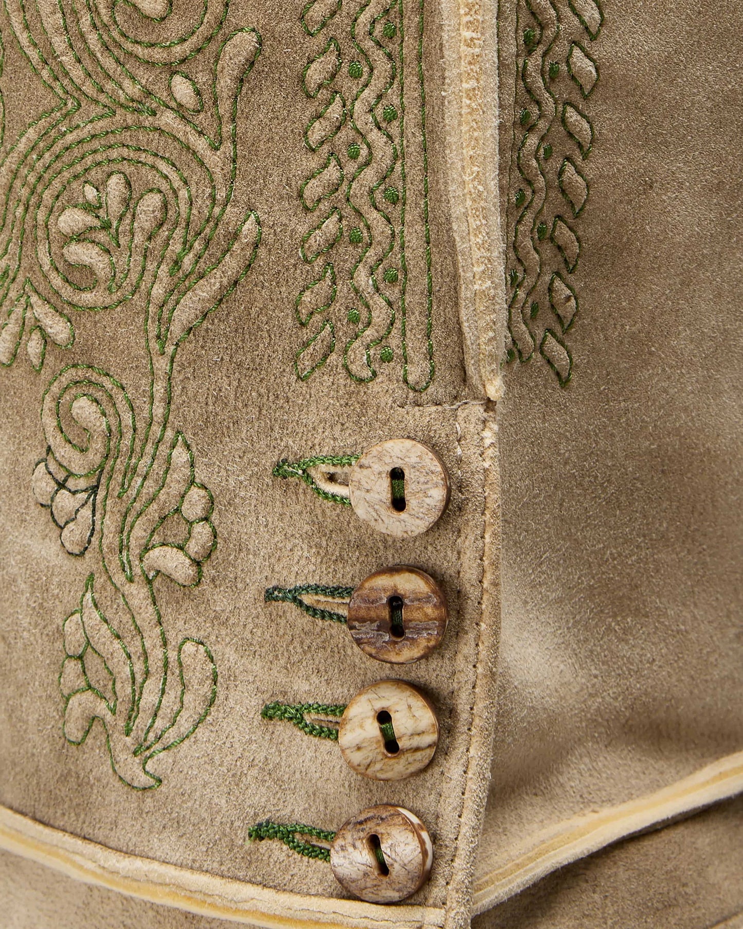 Close-up of a textured fabric with embroidered patterns and buttons.