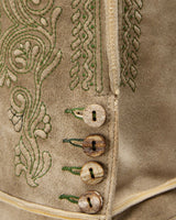 Close-up of a textured fabric with embroidered patterns and buttons.