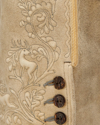 Close-up of a textured surface with intricate designs and buttons on a beige background