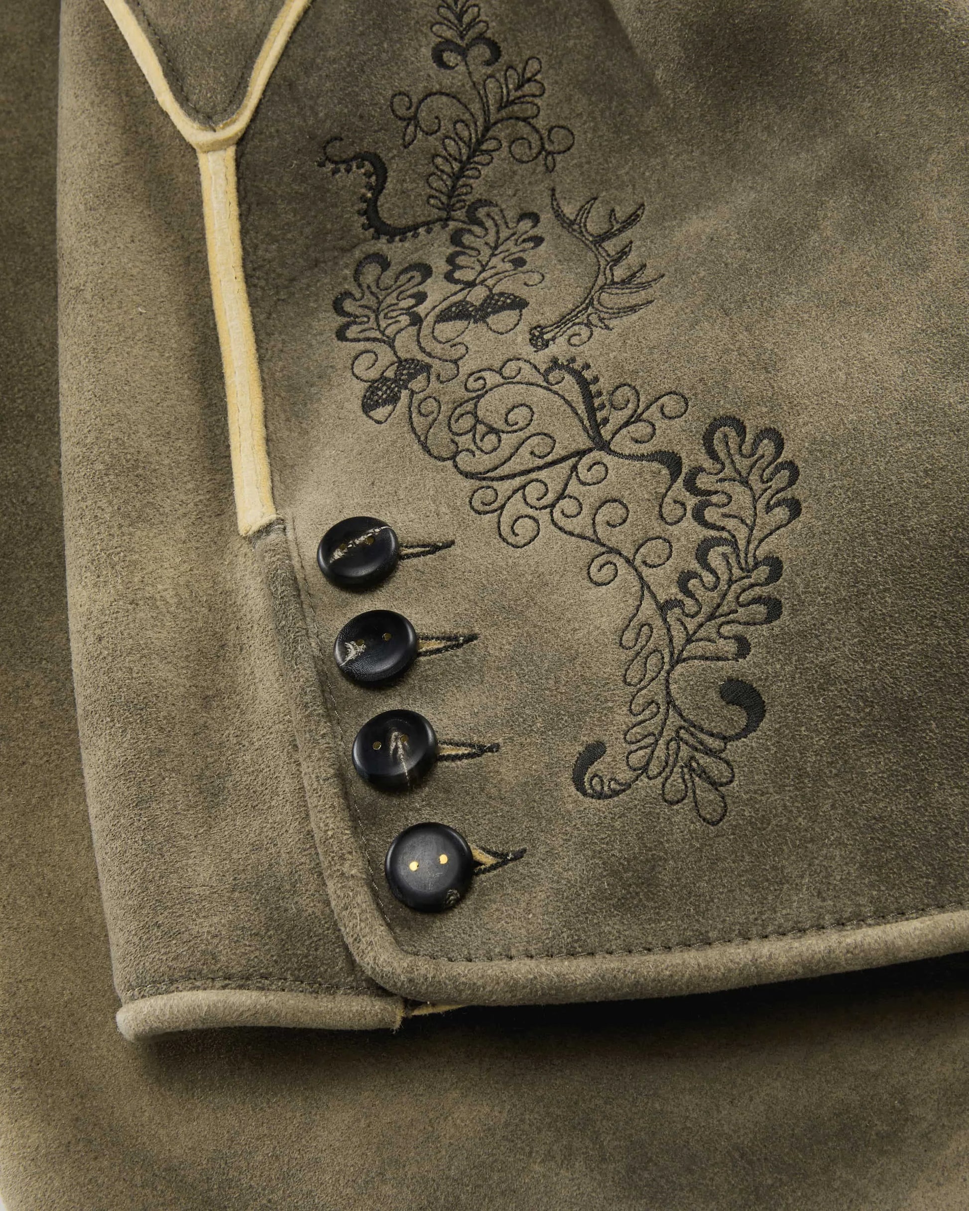Close-up of a brown fabric with embroidered design and buttons.