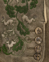 Embroidered design on a fabric with deer and leaves, featuring buttons.