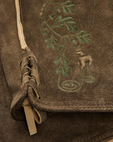 Brown leather bag with embroidered design of a nude figure and foliage.