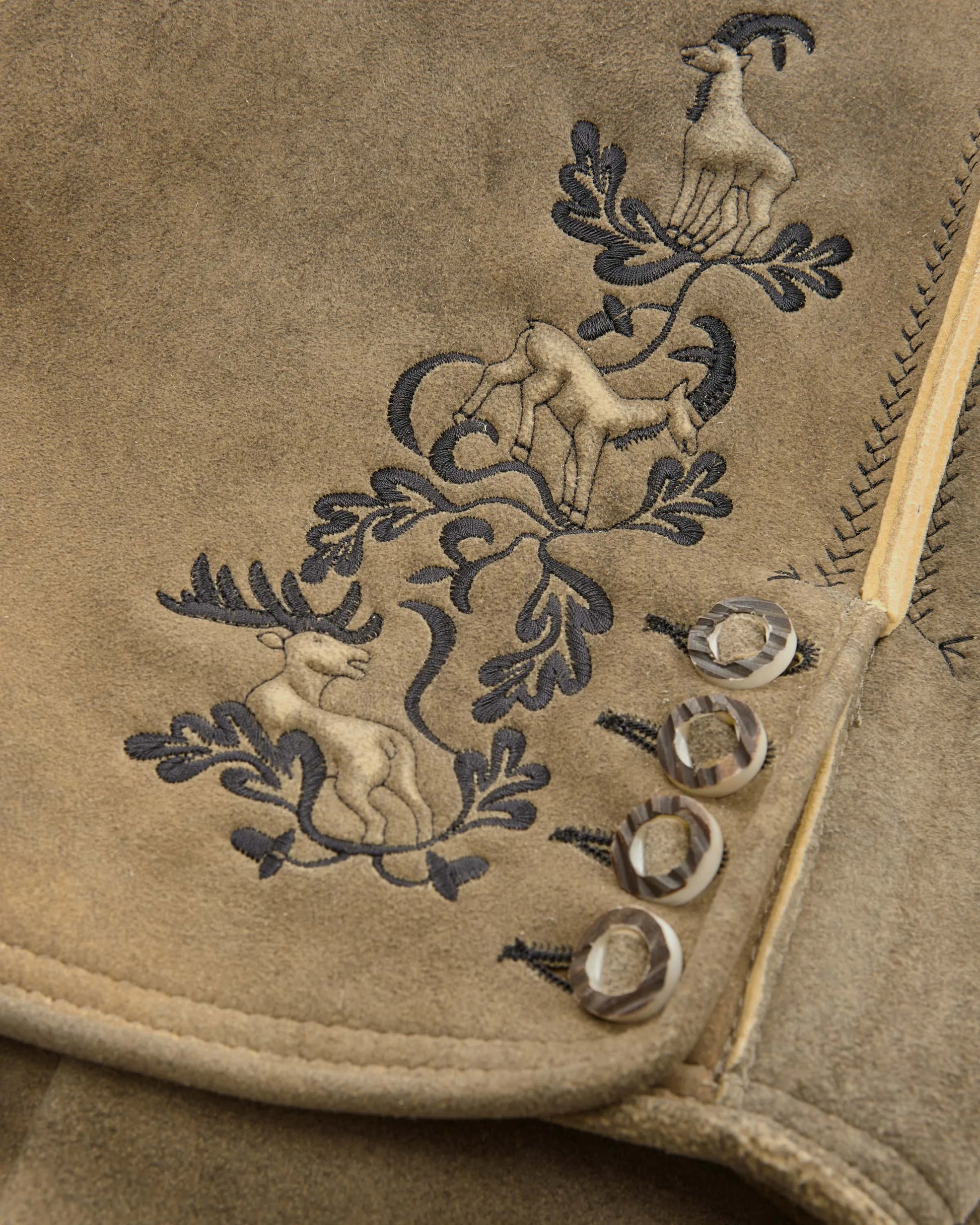 Embroidered design on a beige fabric with animals and leaves.