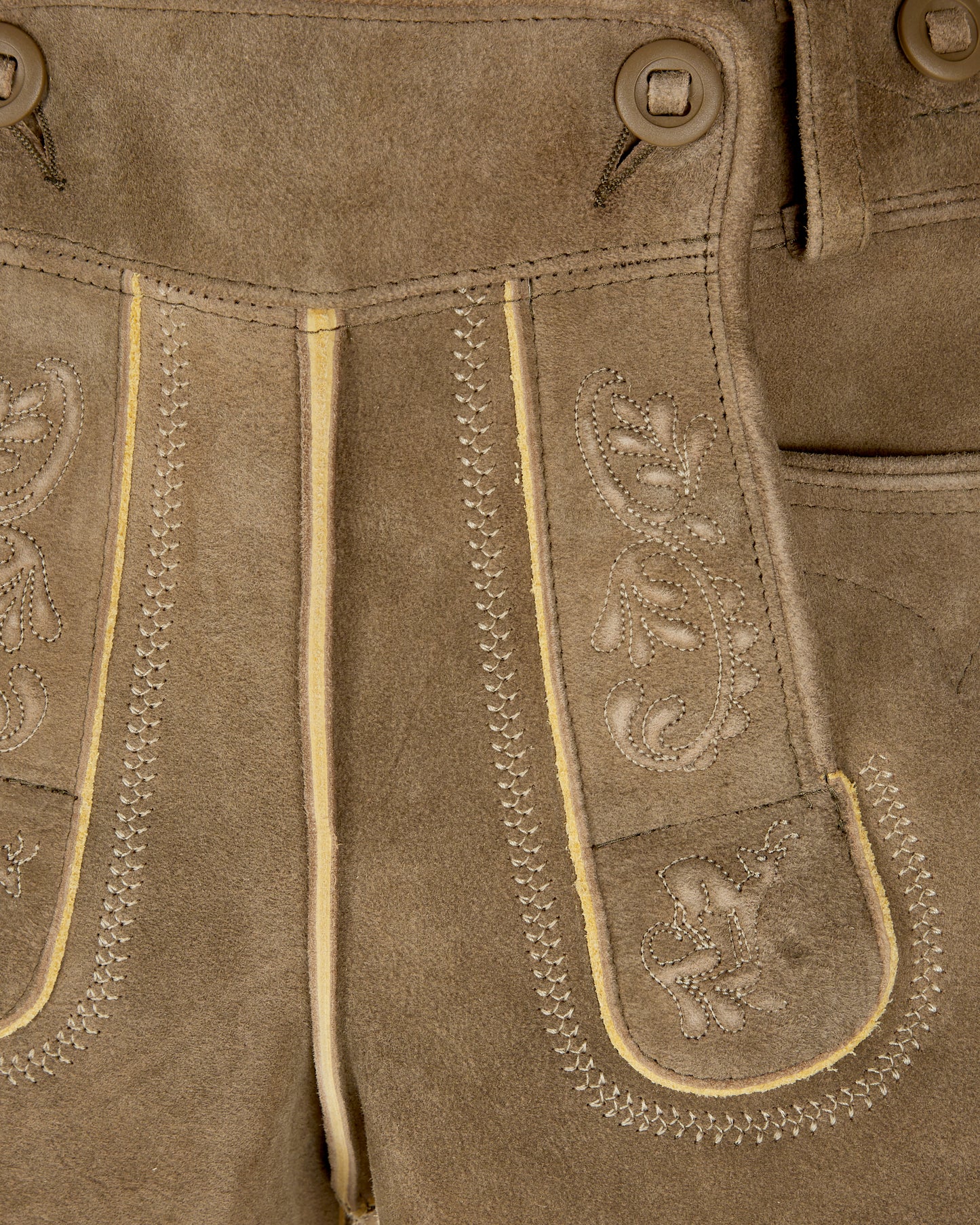 Close-up of brown leather pants with decorative stitching and patterns.