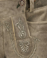 Close-up of a brown leather apron with intricate white embroidery on a matching background.