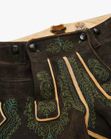 Close-up of a traditional black leather outfit with green embroidery on a white background