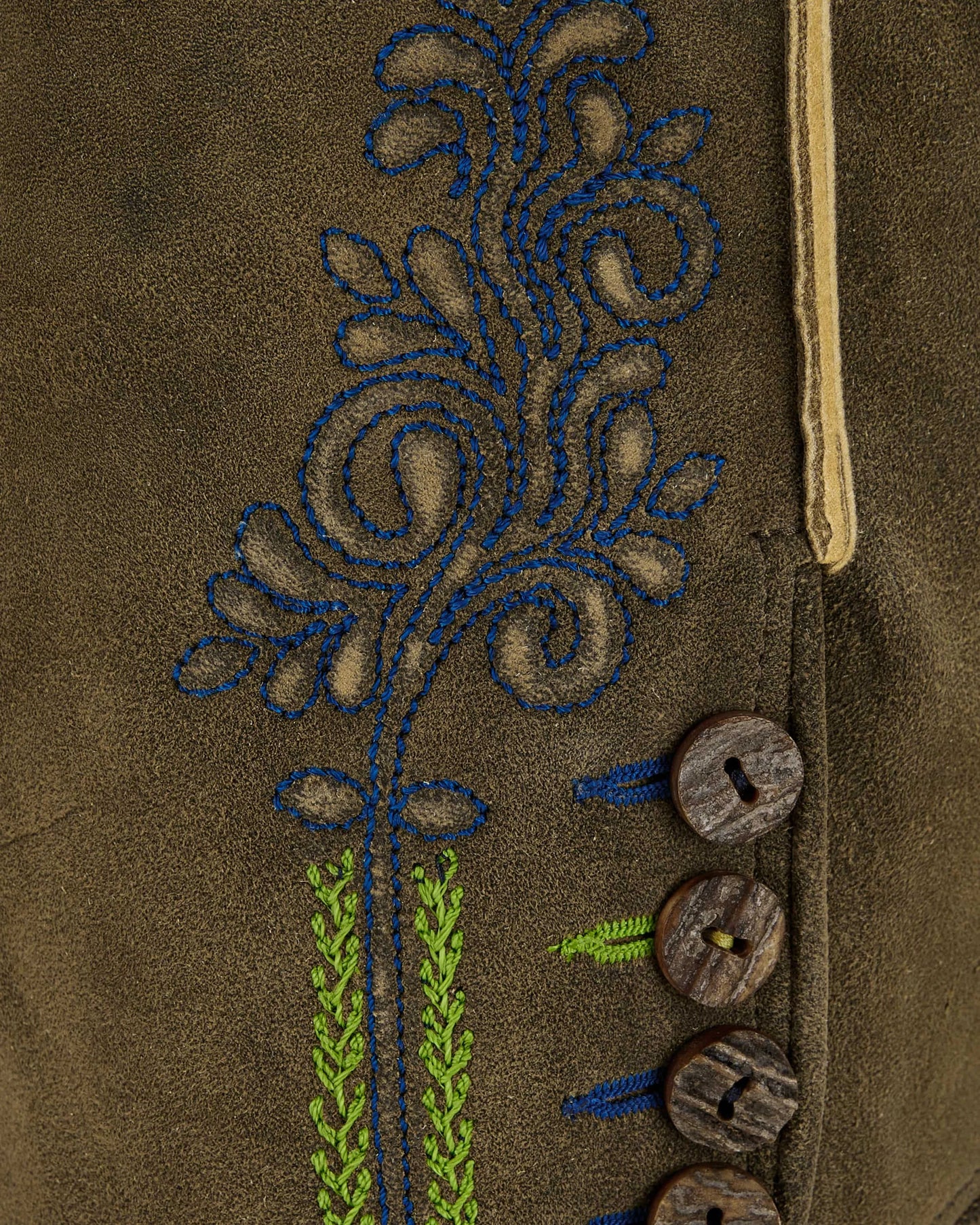 Close-up of a brown fabric with embroidered floral design and wooden buttons.