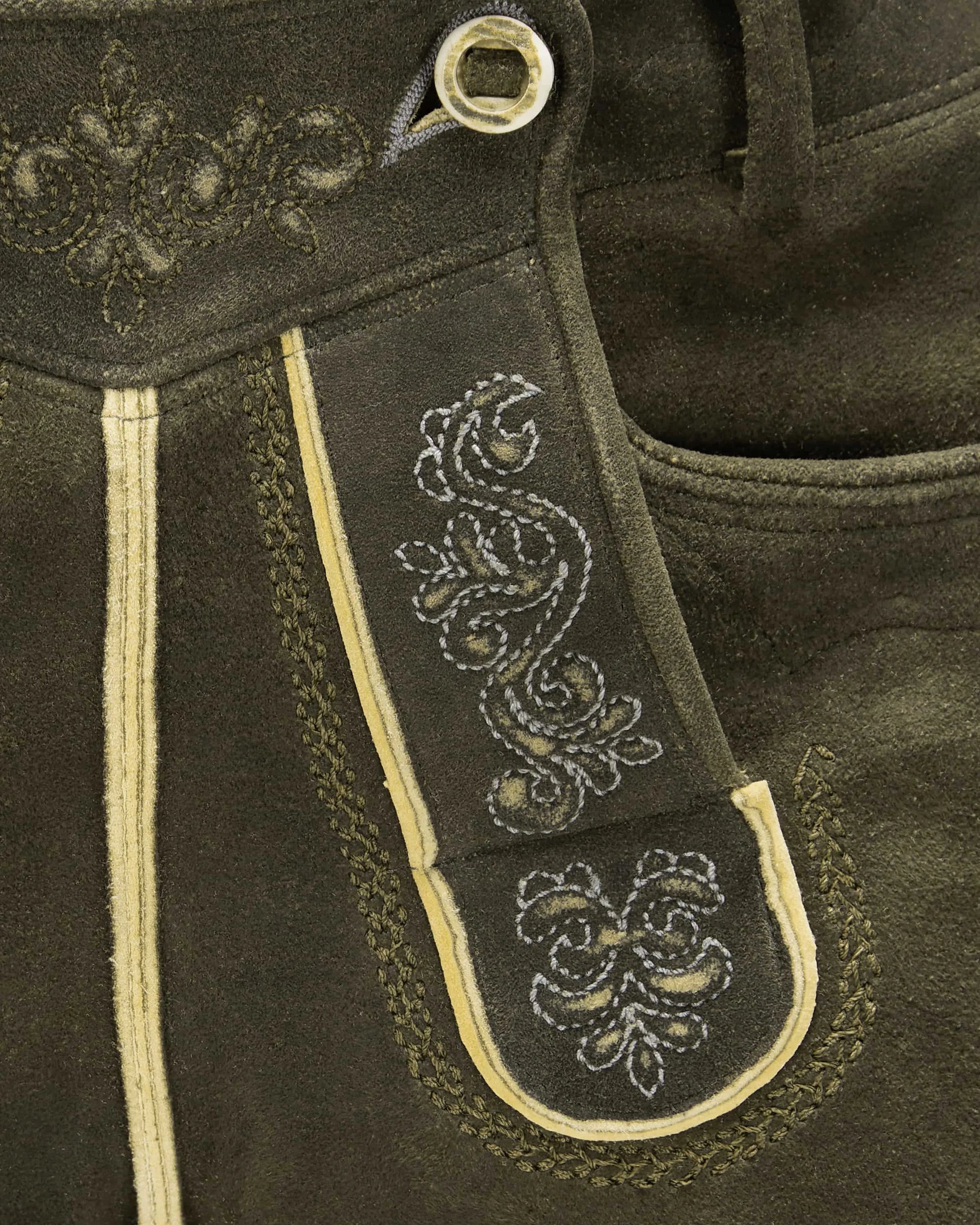 Close-up of dark brown leather with intricate white embroidery on a strap.